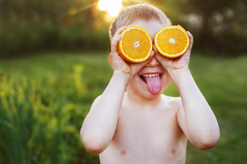 Garçon tenant des oranges jusqu'à ses yeux